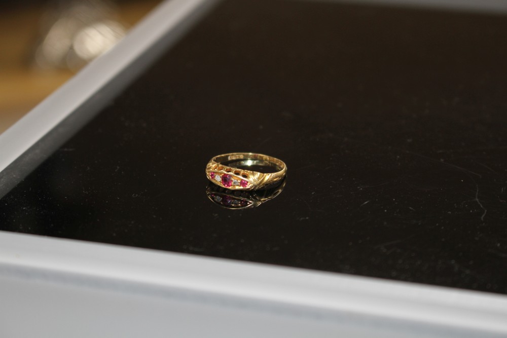 A George V 18ct gold, three stone ruby and two stone diamond set half hoop ring, size P, gross weight 1.9 grams.